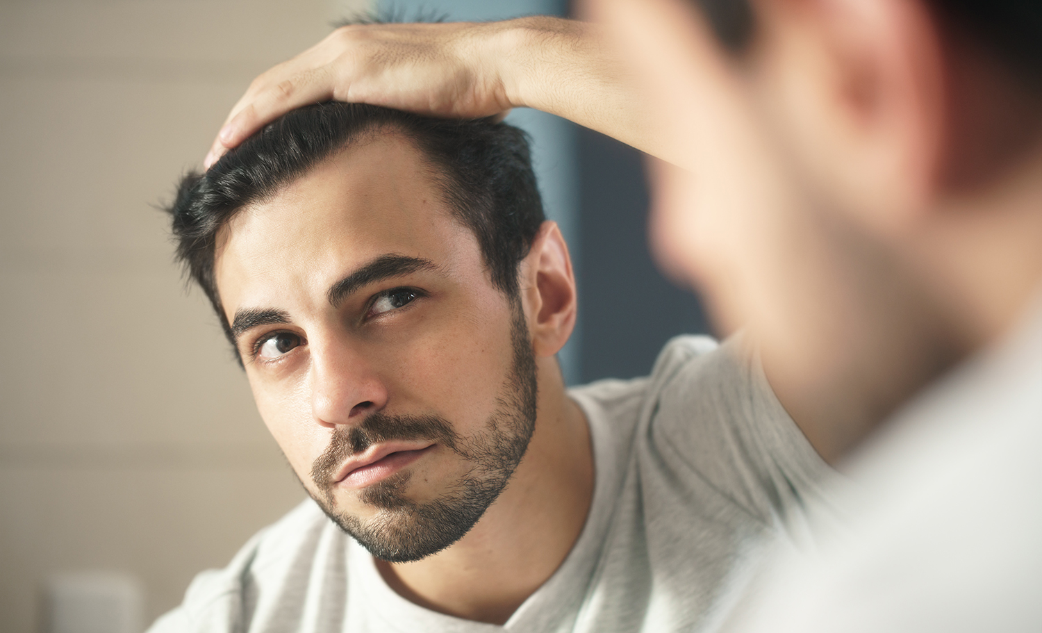 Man looking at his receding hairline in the mirror.